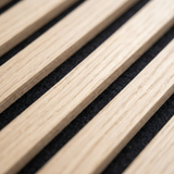 Close-up of light oak wood grain slats with three-sided veneer on black acoustic backing