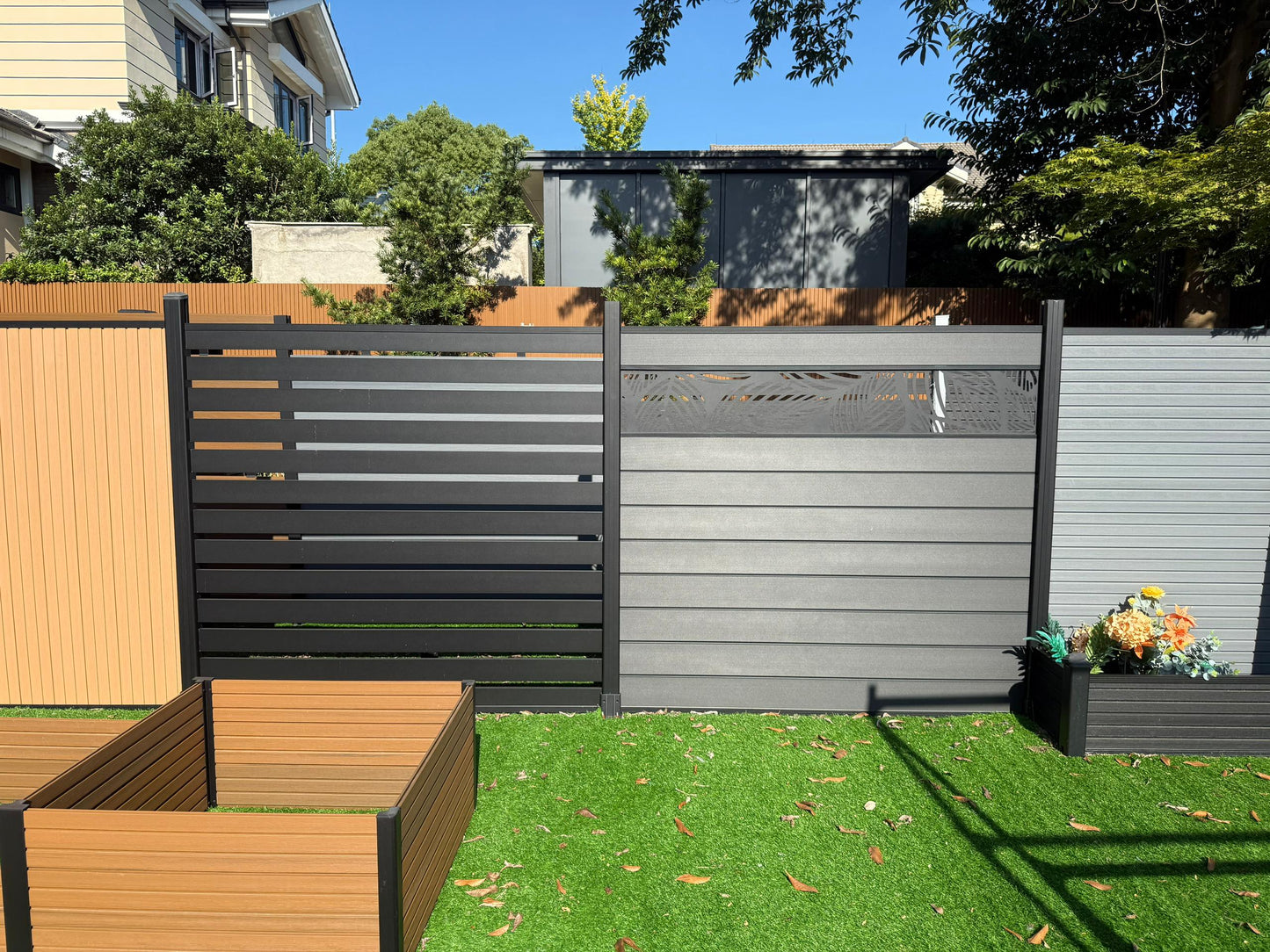 Garden scene with a wooden fence, gray privacy screen, and garden beds.