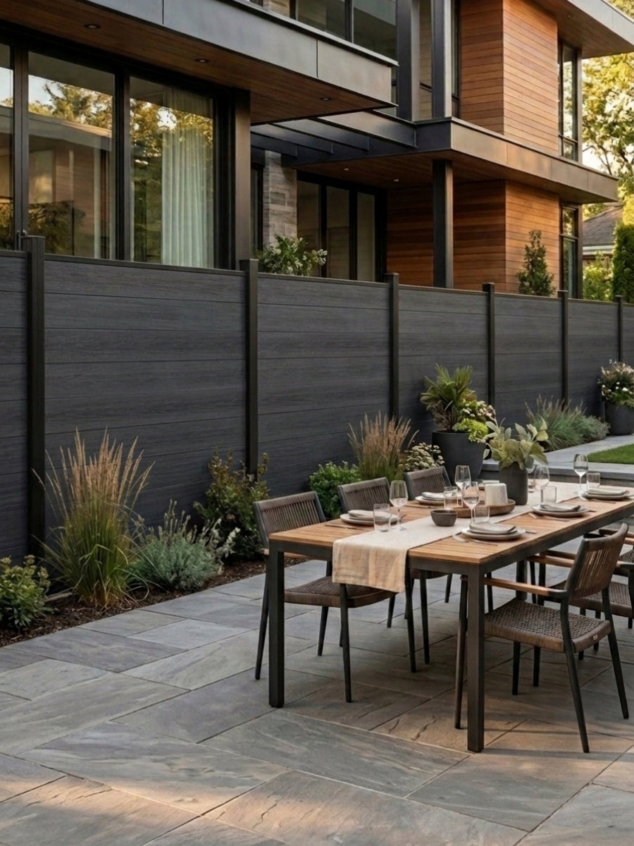 Black composite fence enclosing a modern patio with an outdoor dining table and landscaping