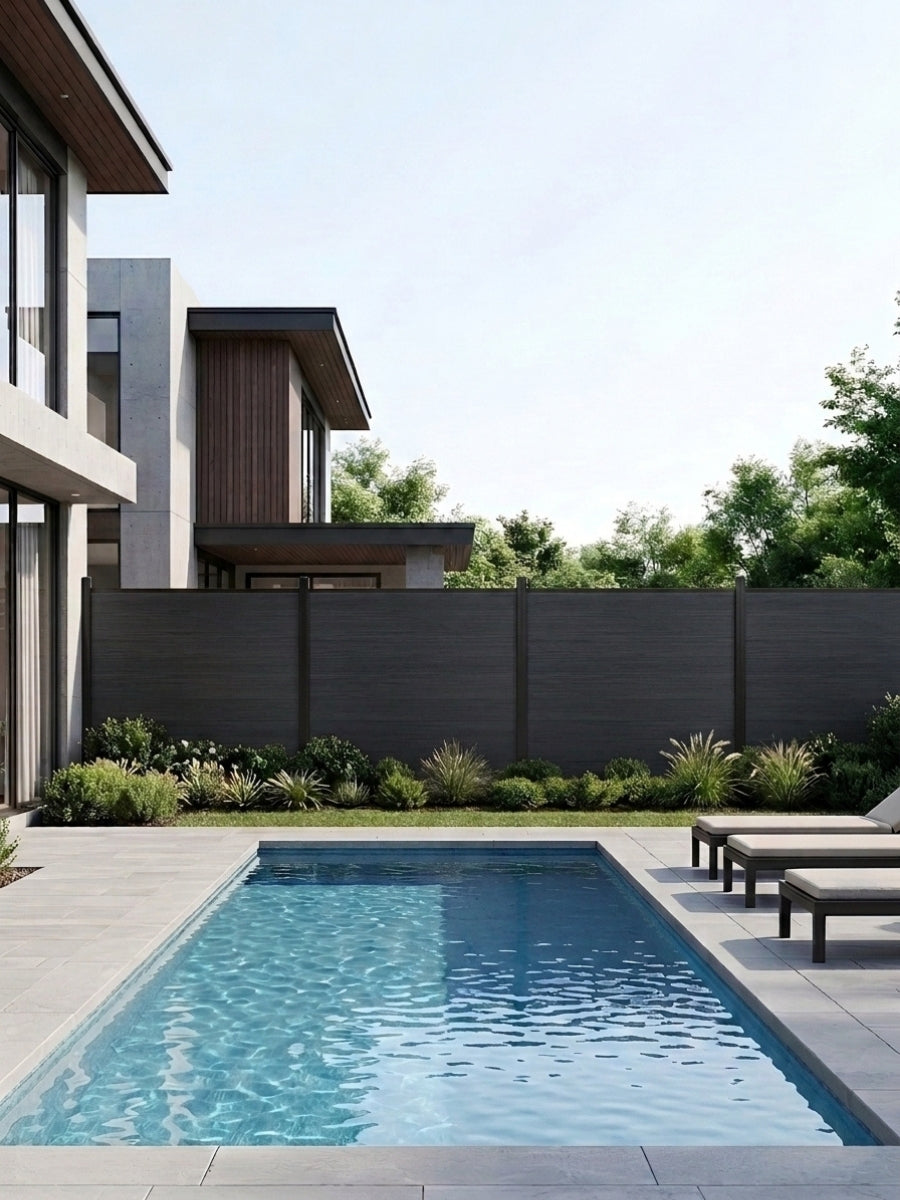 Black composite privacy fence installed behind a modern backyard swimming pool