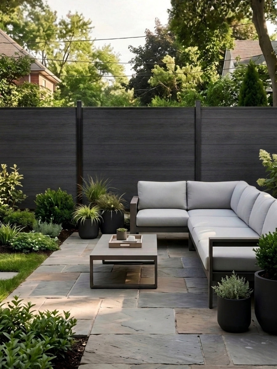 Black composite fence surrounding a landscaped patio with sectional seating