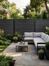 Black composite fence surrounding a landscaped patio with sectional seating