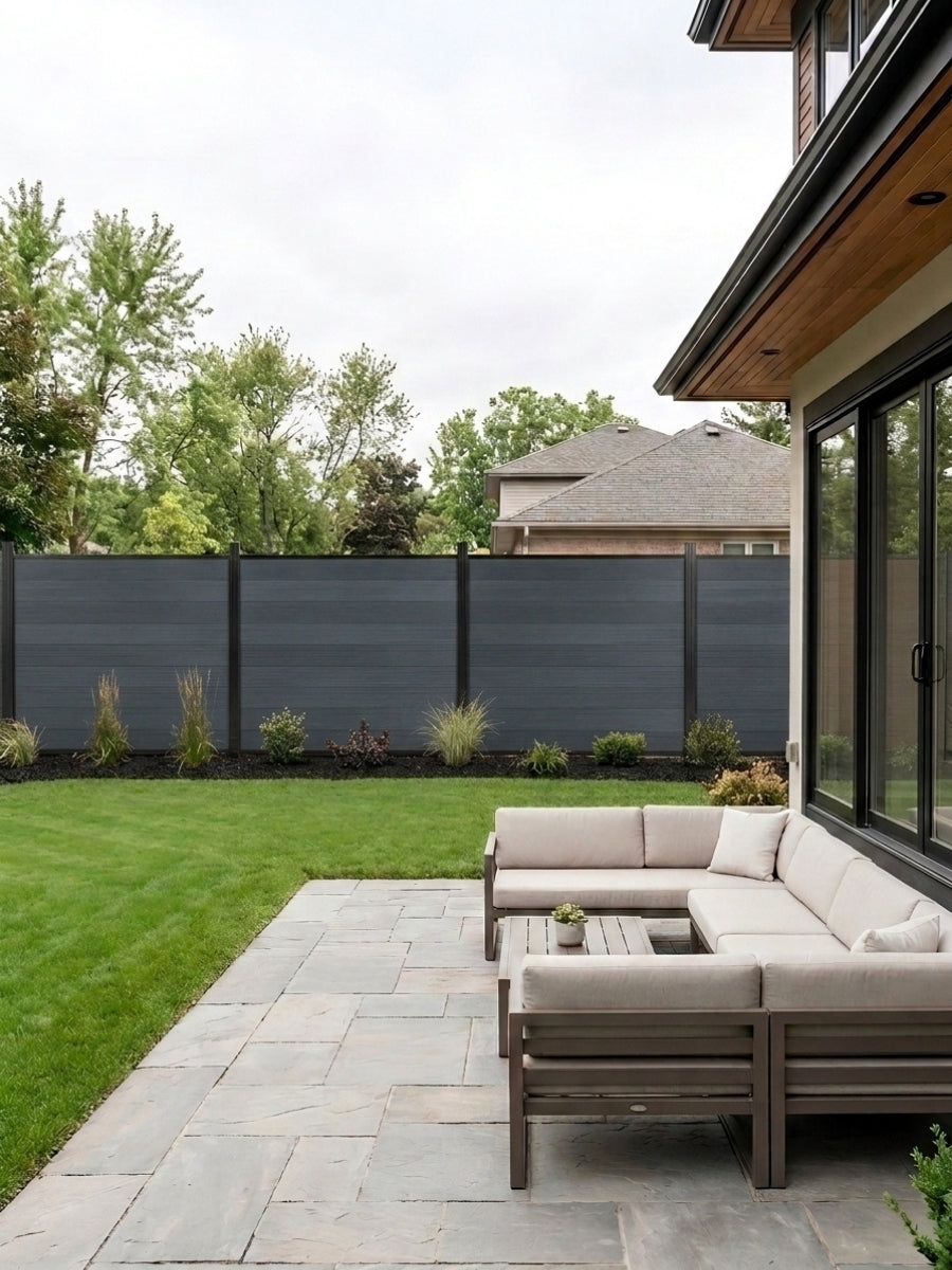 Light gray composite privacy fence installed around a landscaped backyard patio with sectional seating