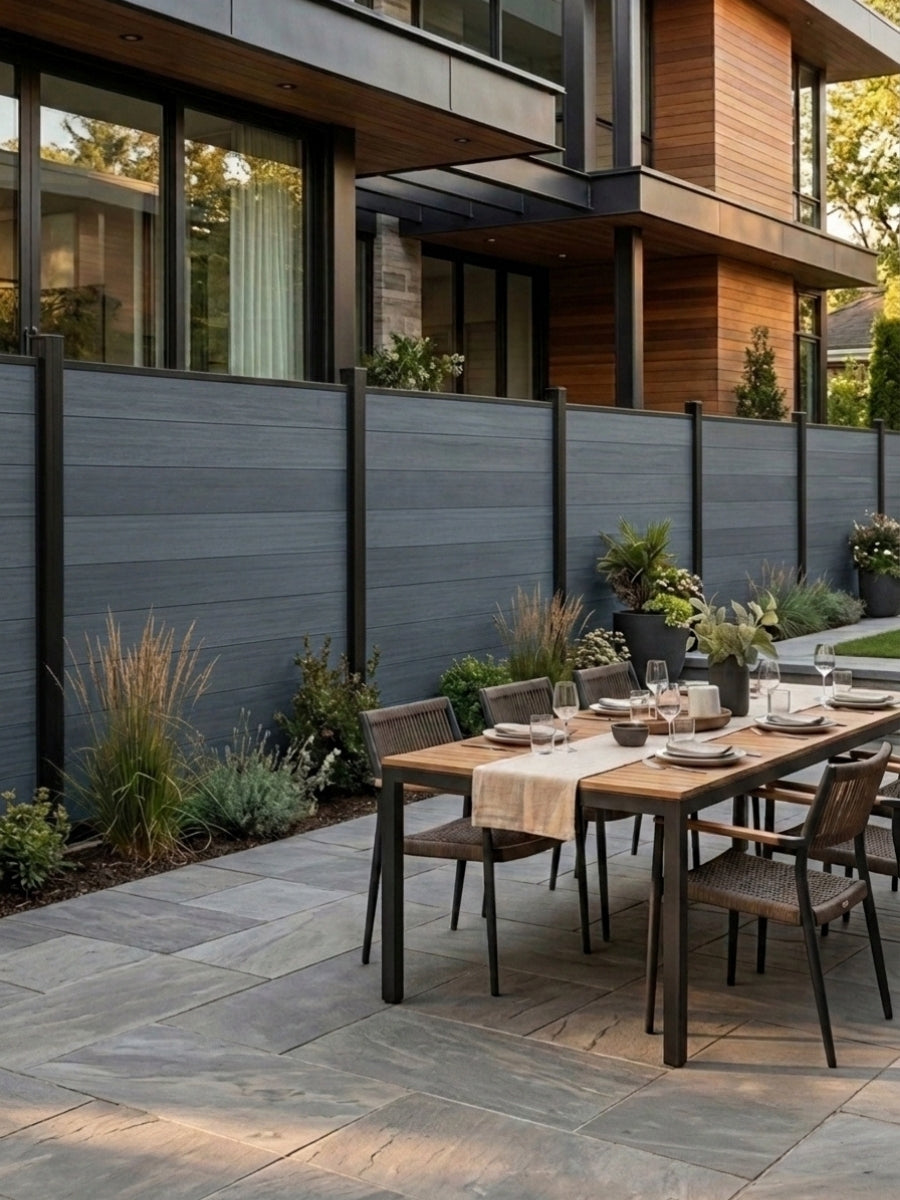 Light gray composite fence enclosing a modern patio dining area beside a contemporary home