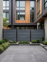 Light gray composite privacy fence installed across a modern paved courtyard garden