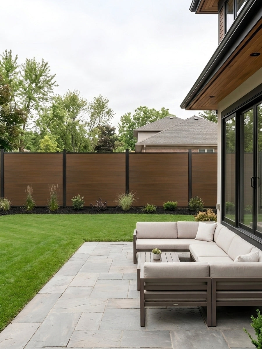 Walnut composite privacy fence installed around a landscaped backyard patio with outdoor sofa