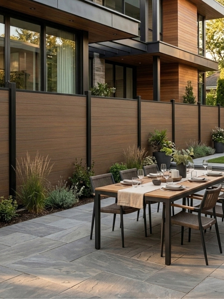 Walnut composite fence enclosing a modern patio with dining table and landscaped border