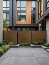Walnut composite privacy fence installed in a modern courtyard with raised garden beds