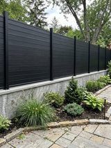 Black aluminum full privacy fence mounted on a concrete garden wall