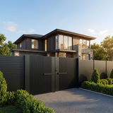 Modern house with a black fence and driveway, surrounded by trees and greenery.
