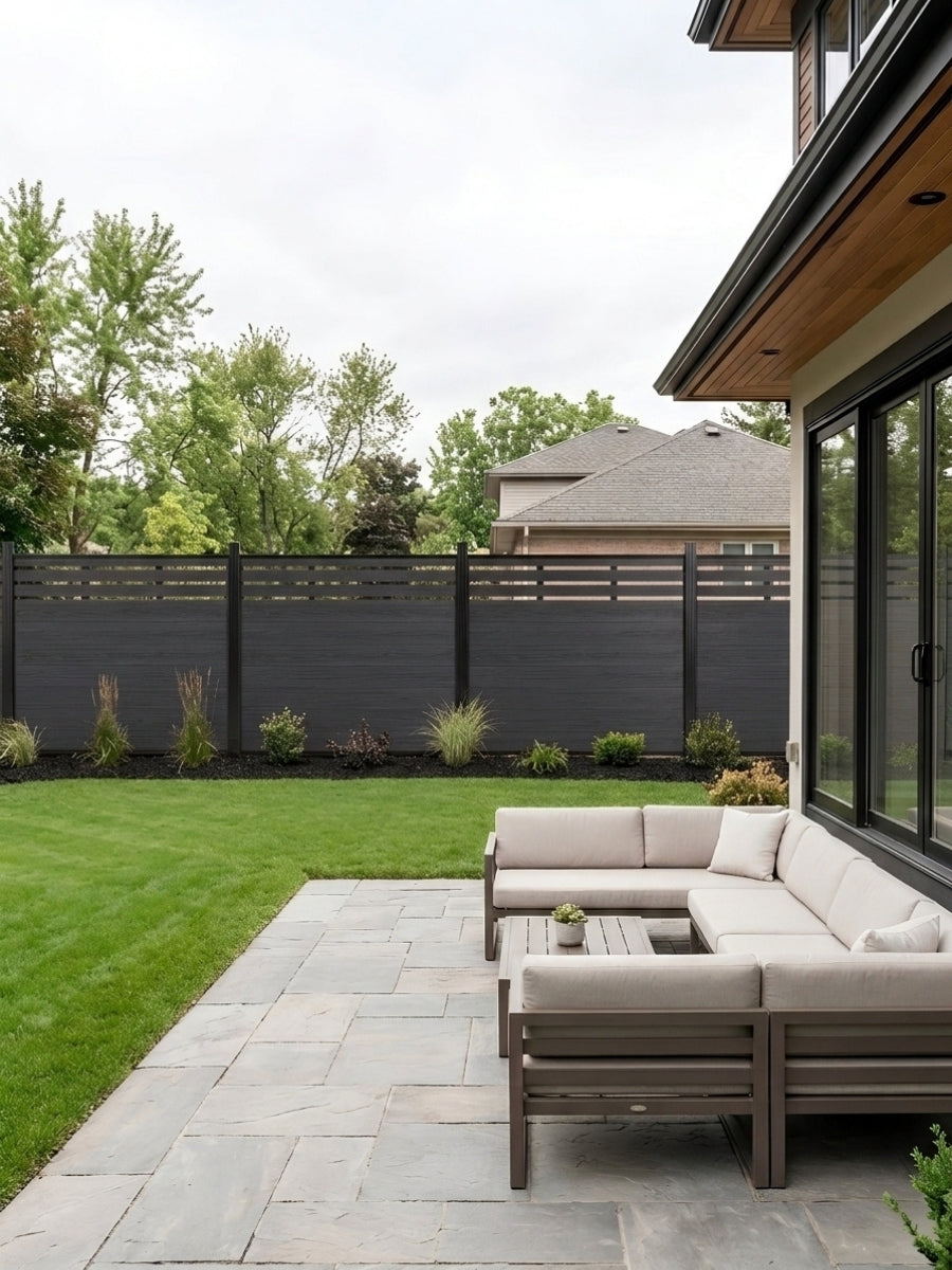 Black composite privacy fence installed around a landscaped backyard patio with outdoor sectional seating