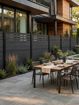 Black top lattice composite privacy fence enclosing a modern patio dining area with garden beds