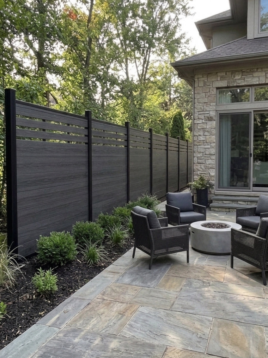 Black top lattice composite fence installed beside a stone patio with outdoor chairs and fire pit