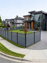 Light gray composite privacy fence enclosing a corner lot with lawn and modern house