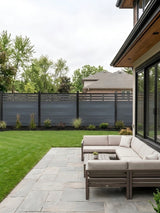 Light gray top lattice composite privacy fence installed around a landscaped backyard patio
