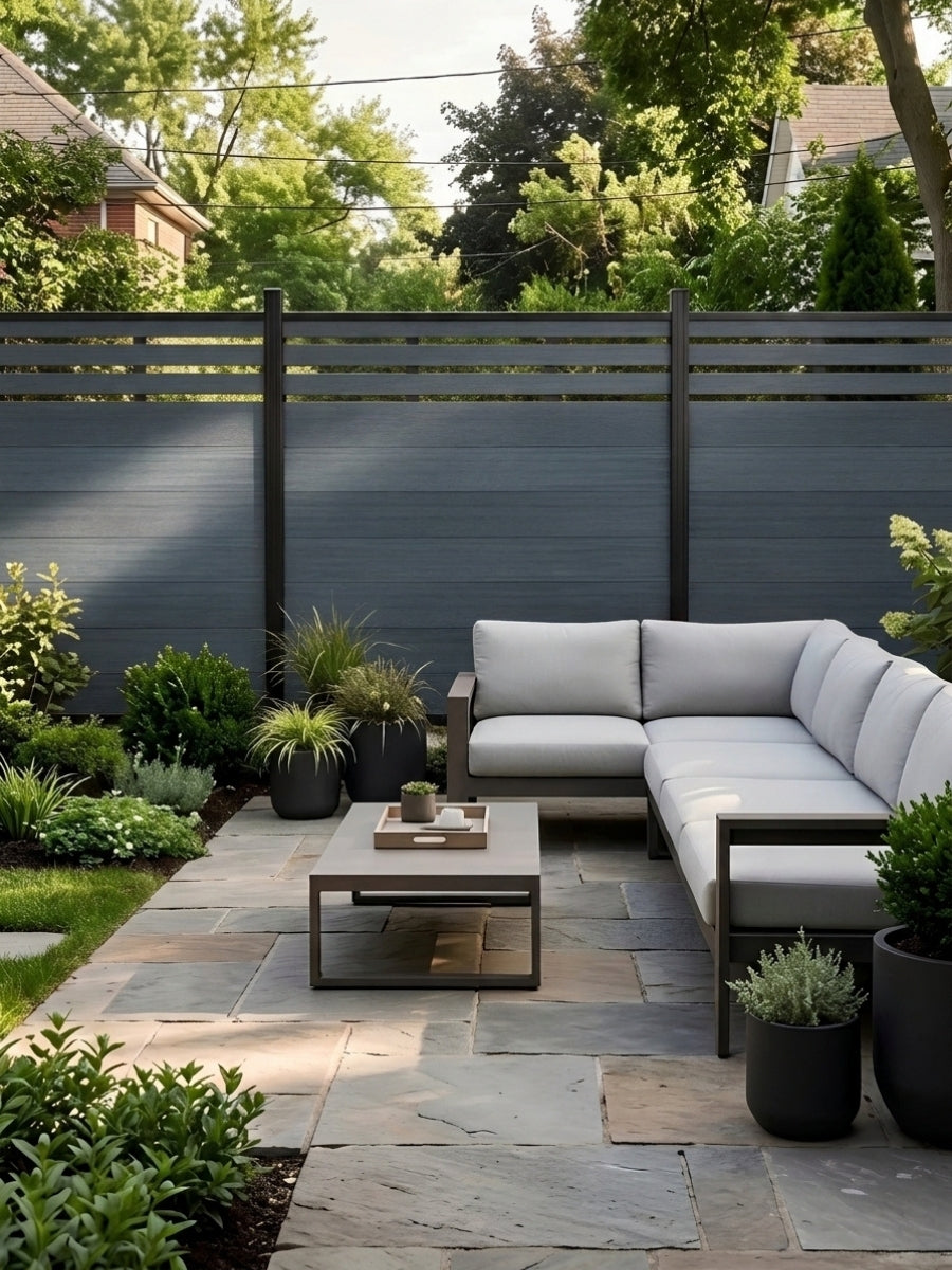 Composite privacy fence with slatted top behind a garden patio and sectional sofa