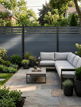 Composite privacy fence with slatted top behind a garden patio and sectional sofa