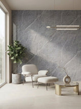 Ash gray marble PVC wall panel behind a cream lounge chair, ottoman, plant, and coffee table