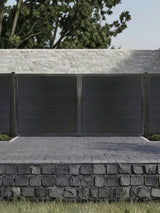 Black WPC double fence gate with horizontal privacy panels installed at a residential driveway with matching fencing and stone retaining wall.