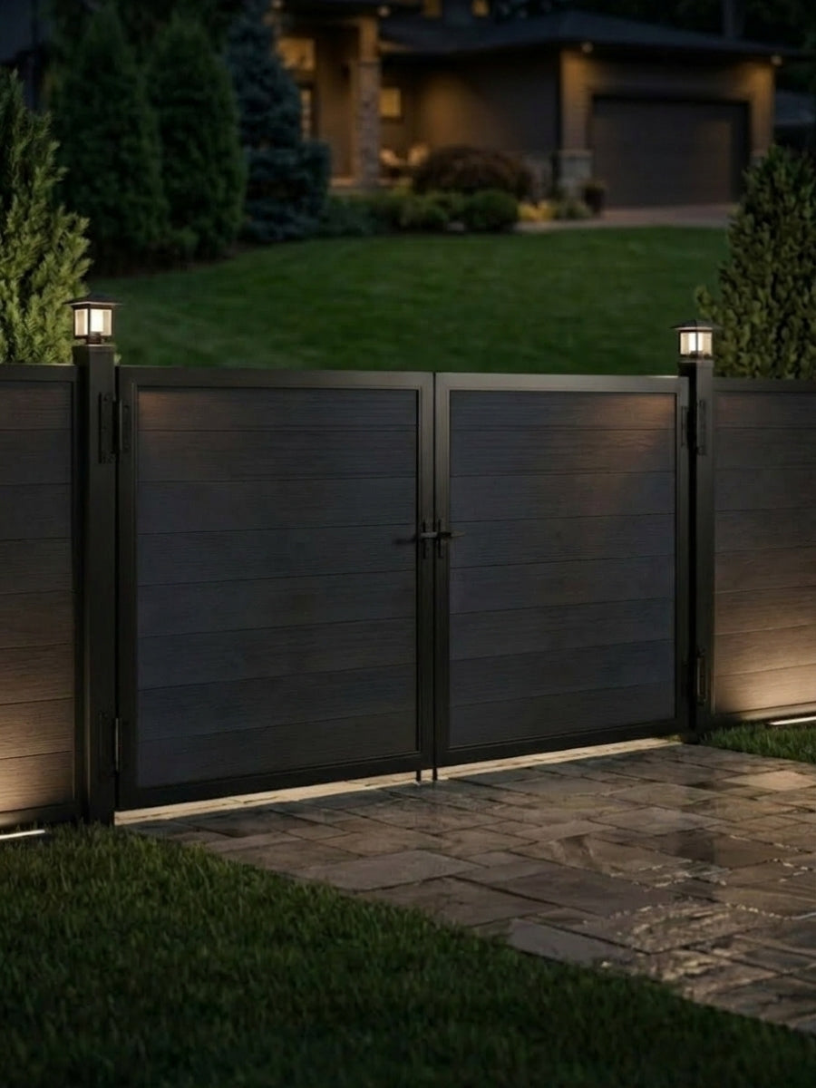 12ft x 6ft black WPC double fence gate with horizontal privacy panels installed at a residential driveway with illuminated gate posts at night.