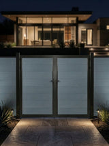 8ft x 6ft gray WPC double fence gate with black frame illuminated along a walkway outside a modern home at night