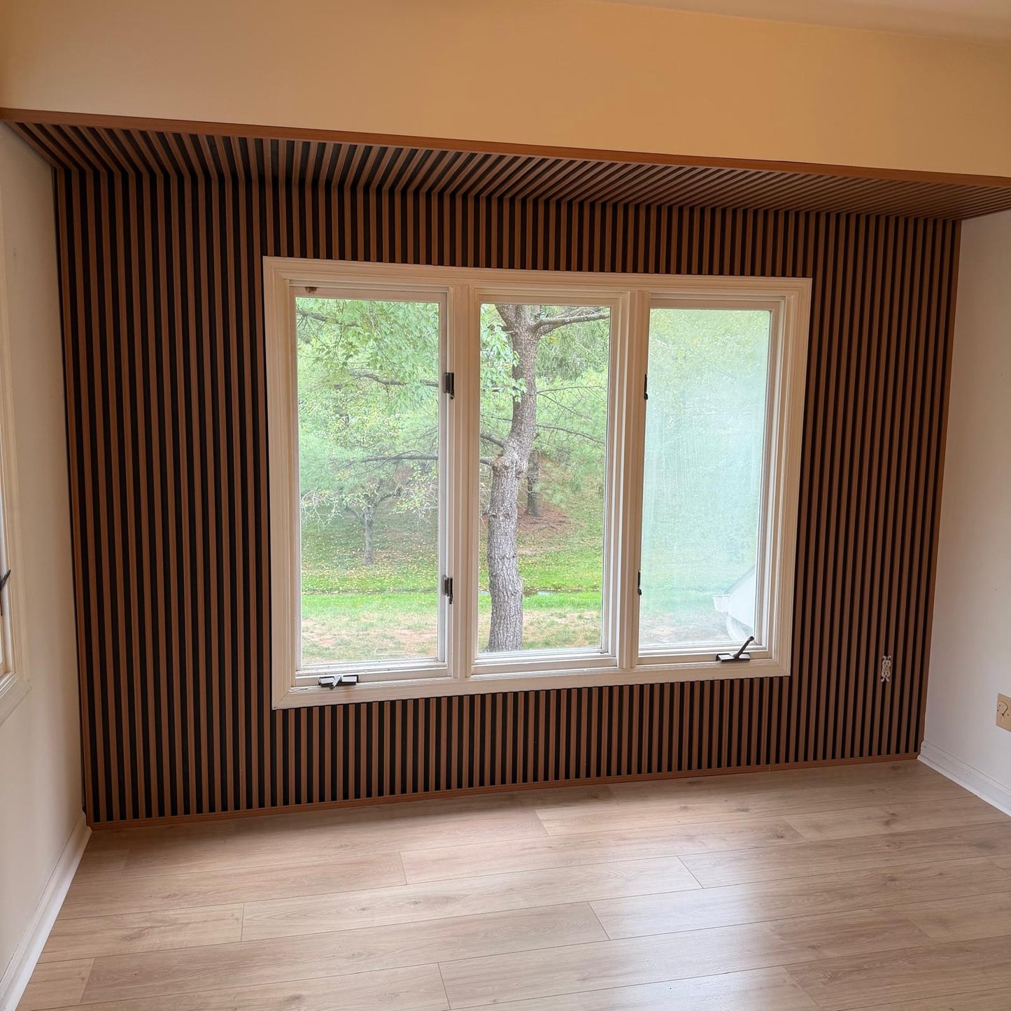 Oak gray WPC fluted wall panels installed around window creating a modern vertical slat accent wall